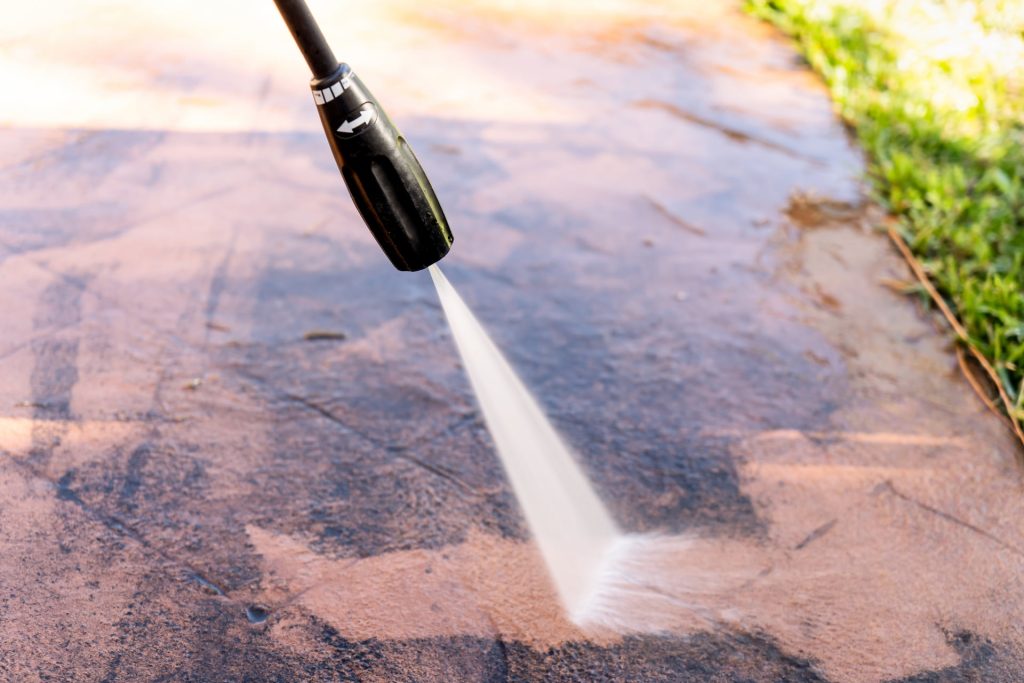 closeup image of a pressure washing nozzle cleaning a concrete walkway